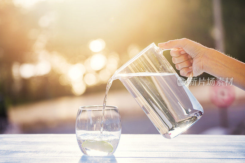 把水从水罐倒进玻璃杯里