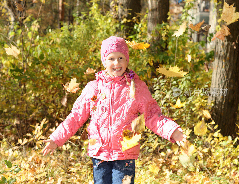 小女孩在玩秋天的树叶