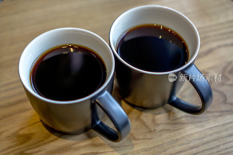 木桌上放着两杯黑咖啡