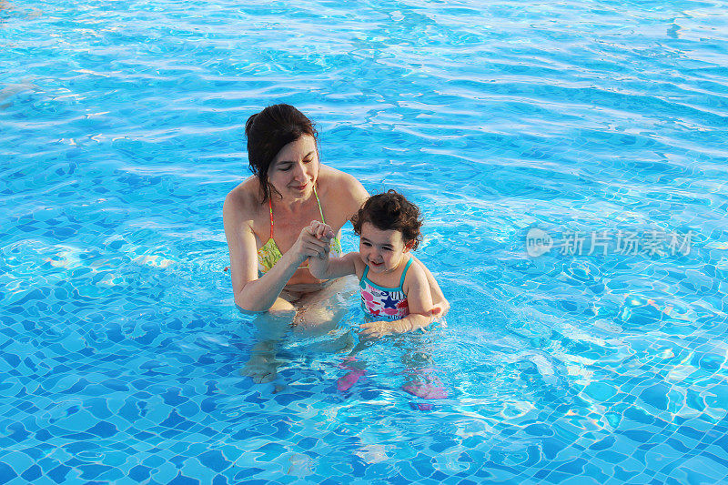 妈妈和女儿在游泳池里