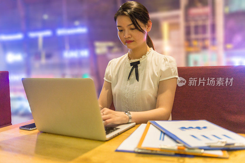 一个年轻的亚洲女人在深夜用笔记本电脑工作