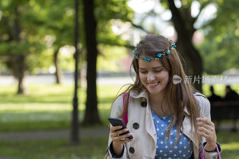 一个好女孩正在公园里散步，正在用手机写短信