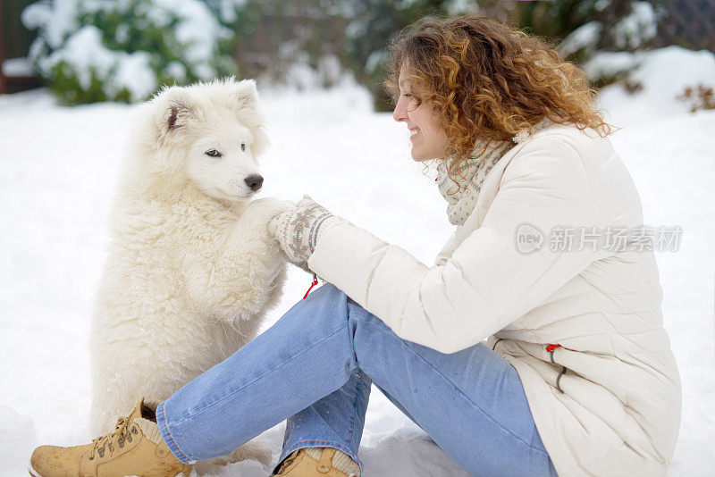 年轻女子在冬季公园和白色的狗