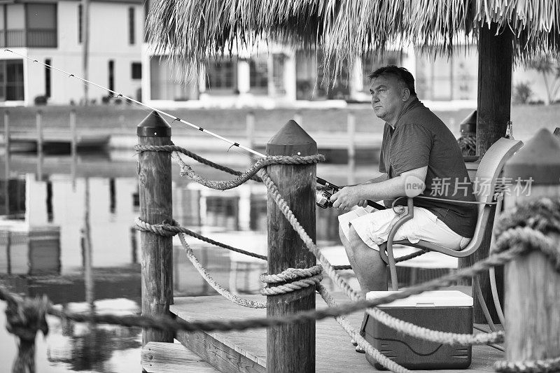 一个成熟的男人在码头上钓鱼