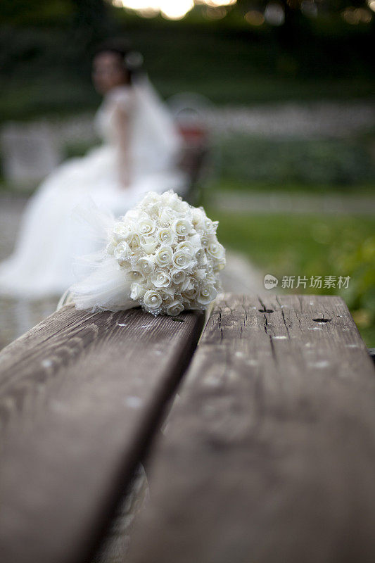 年轻孤独的新娘穿着婚纱站在公园里