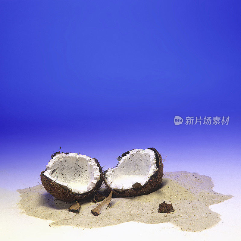 切片的椰子躺在沙蓝色的背景摄影