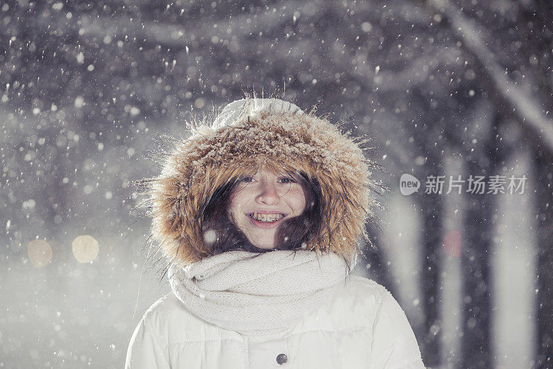 雪下穿着白色夹克的漂亮少女