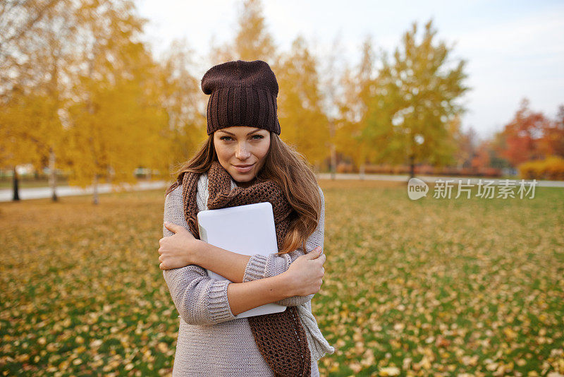 美丽的年轻女子和她的数字平板电脑在公园里