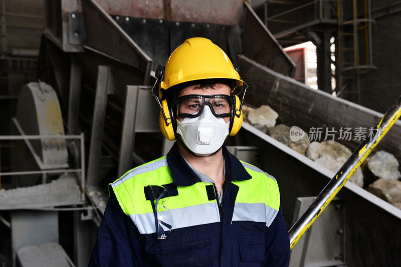 在破碎机生产线附近戴着防护口罩的工人