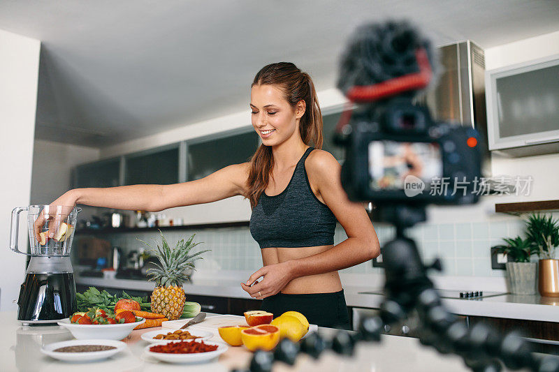 年轻女性博客录制内容的视频博客在厨房。