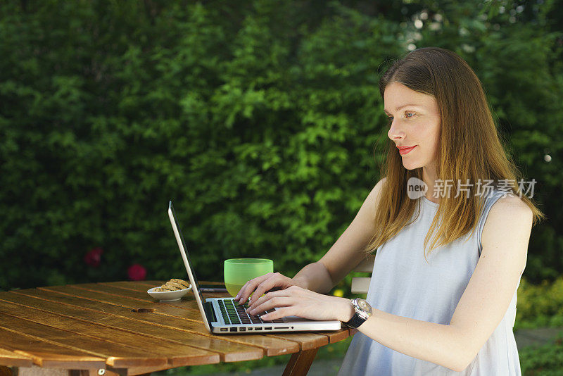 女人们坐在户外的桌子旁使用笔记本电脑