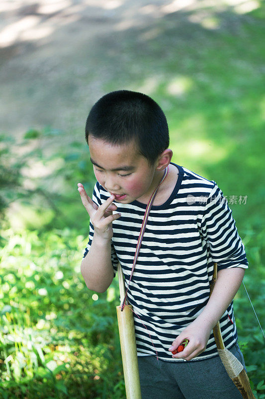 亚洲男孩拿着弓箭在森林里