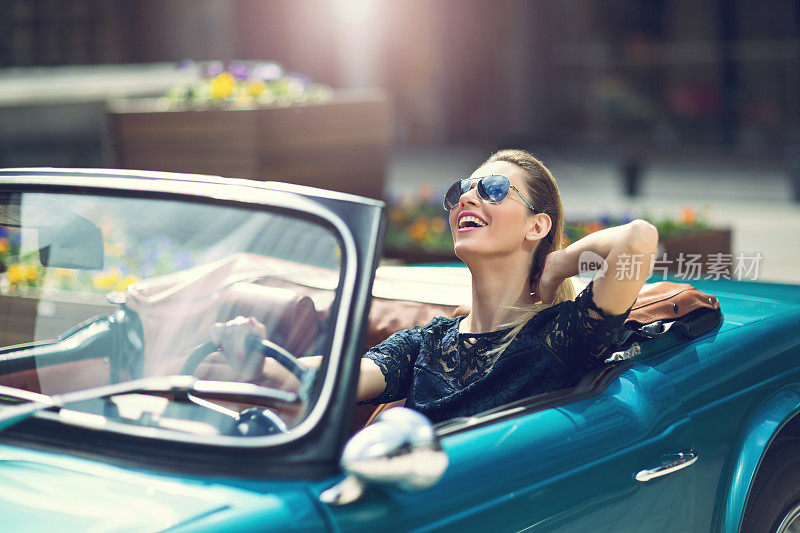 时尚女模特戴着太阳镜坐在豪华复古车里