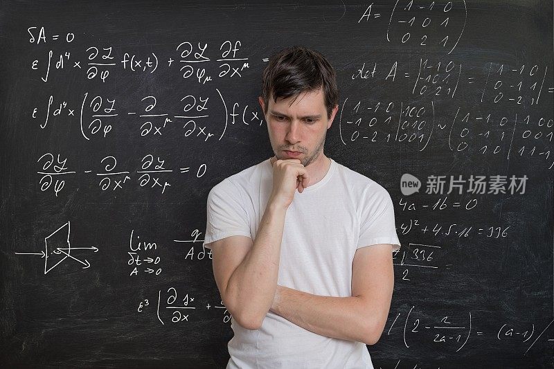 年轻的学生正在解决数学考试。背景黑板上的数学公式。