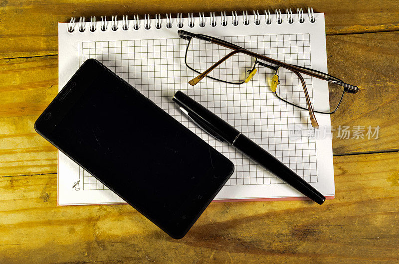 钢笔、智能手机和笔记本上的眼镜