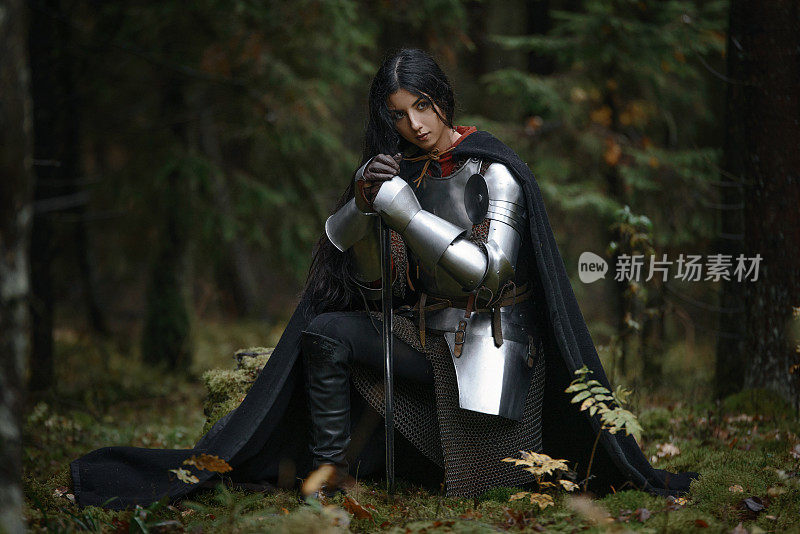 一个美丽的战士女孩带着剑，穿着链甲和盔甲在一个神秘的森林。