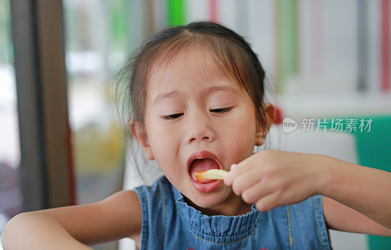 快乐的小女孩吃着炸薯条。