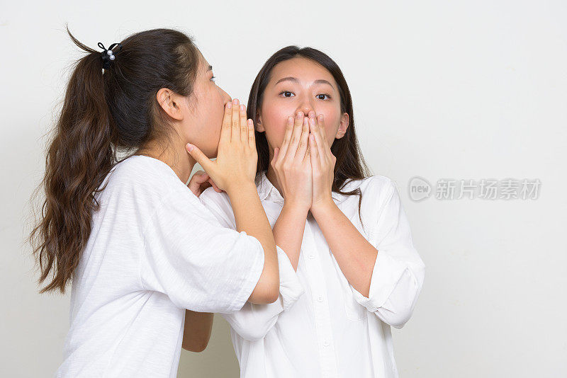 两个年轻美丽的韩国女性朋友一起反对白色的背景