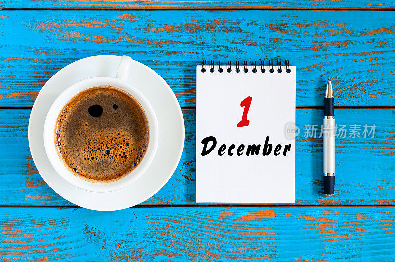 12月1日。每月第一天，用咖啡杯在非正式的工作场所背景上俯视图日历。冬天
