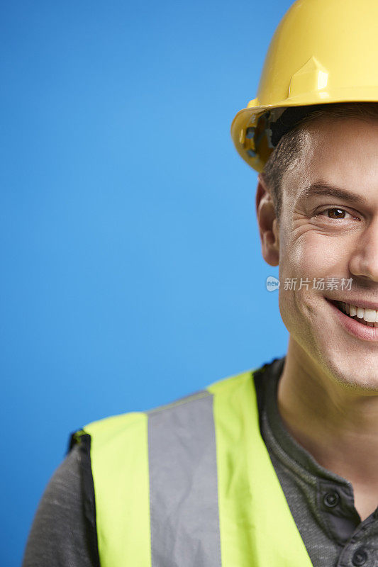 微笑的年轻建筑工人戴着安全帽，垂直作物