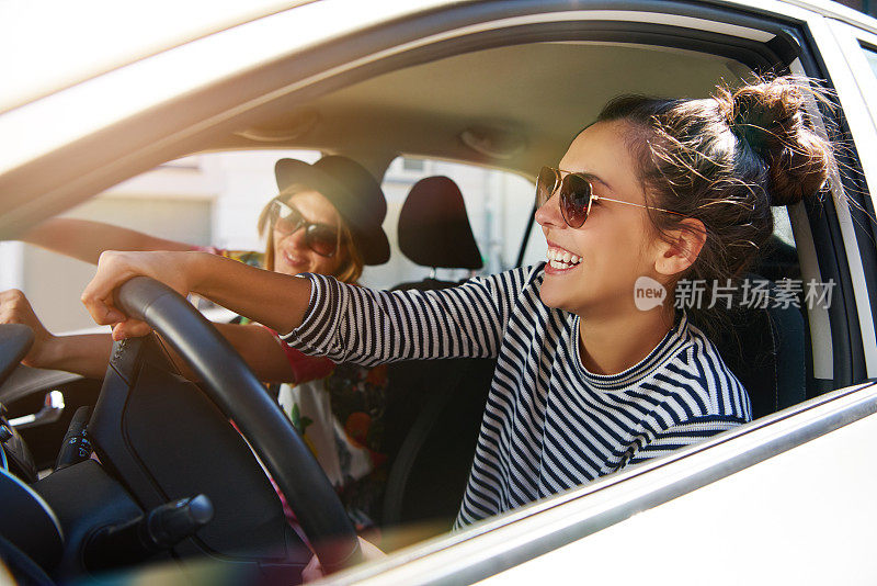 两个笑着的年轻女友一起开车