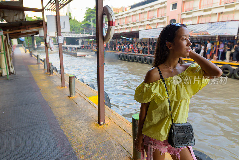 年轻美丽的多民族旅游妇女的肖像在水出租车站在泰国曼谷