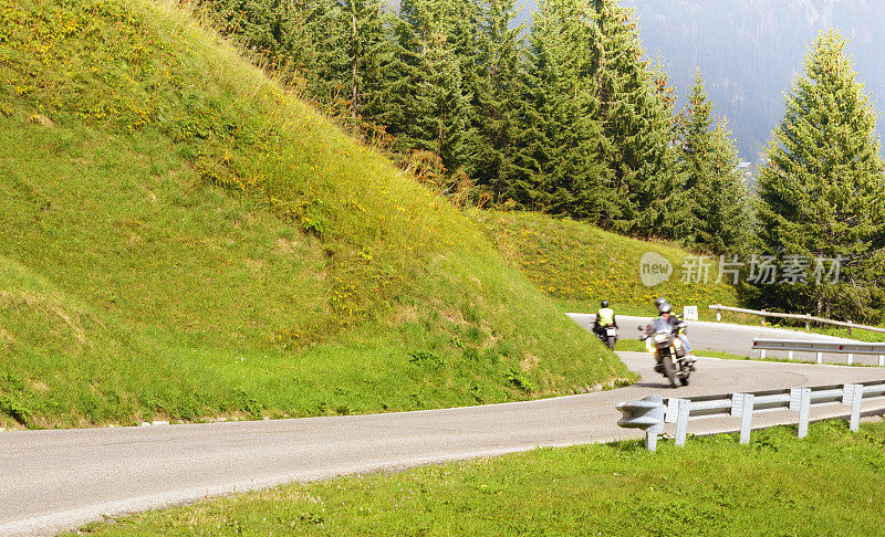 在欧洲阿尔卑斯山的山路上骑摩托车的人。