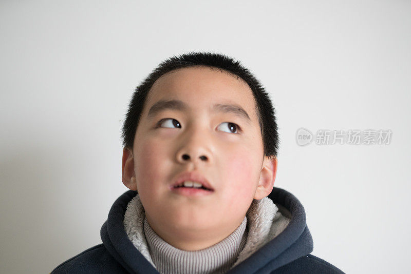 亚洲小学男孩站在家里的白墙前