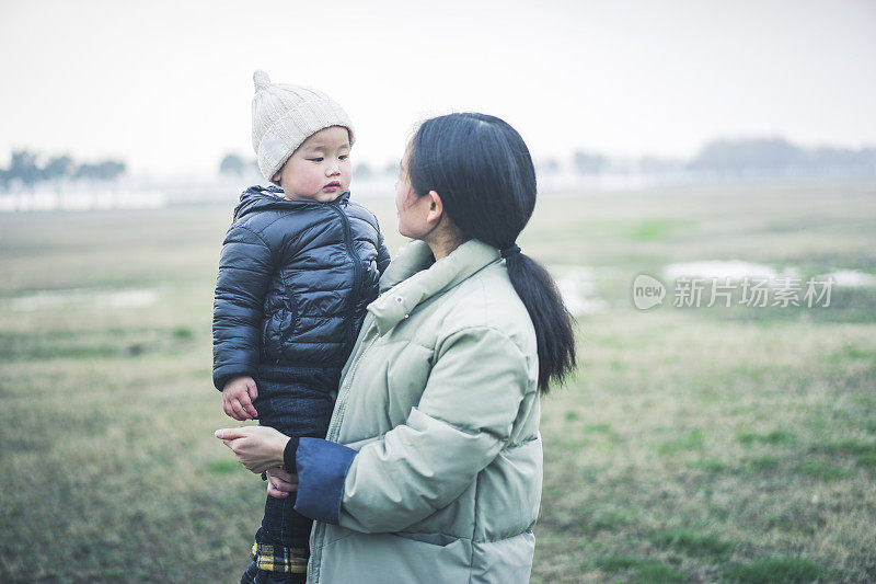 年轻的母亲在草地上抱着儿子