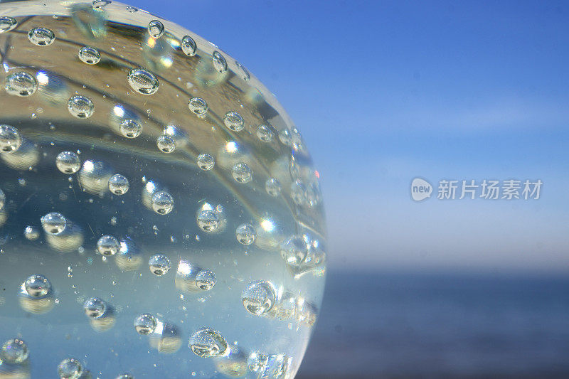 阳光反射在沙滩上的玻璃球上