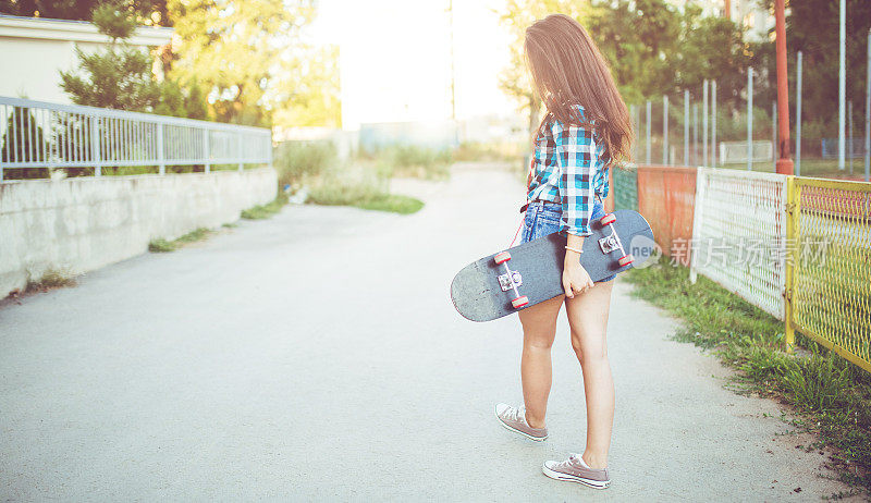 女孩滑着滑板走在街上