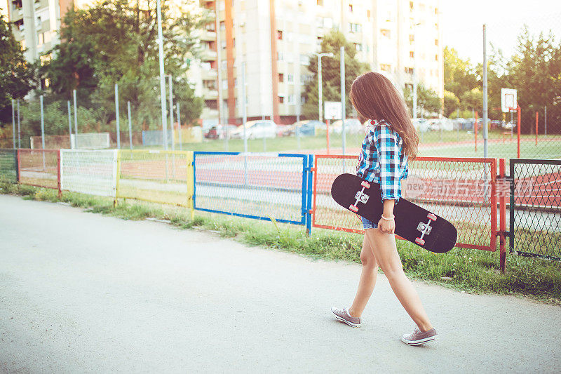 女孩滑着滑板走在街上