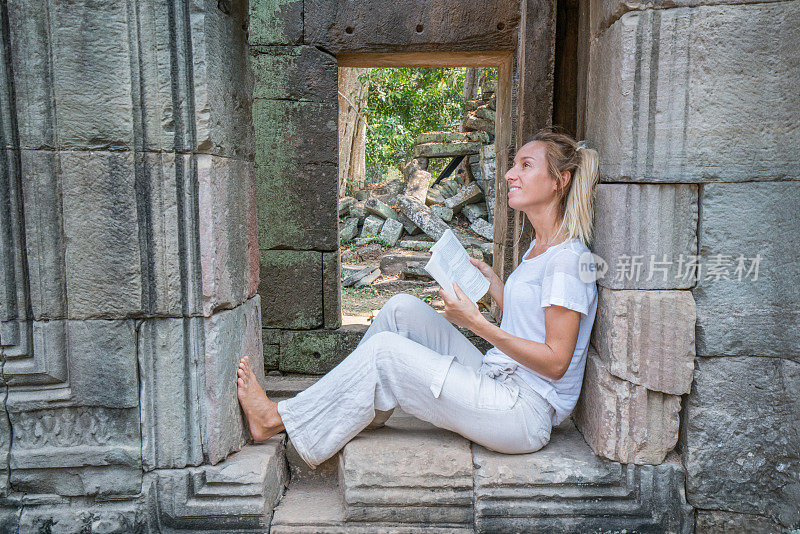 友好美丽的女性旅行者拿着旅游指南阅读关于柬埔寨吴哥窟建筑群的旅游信息