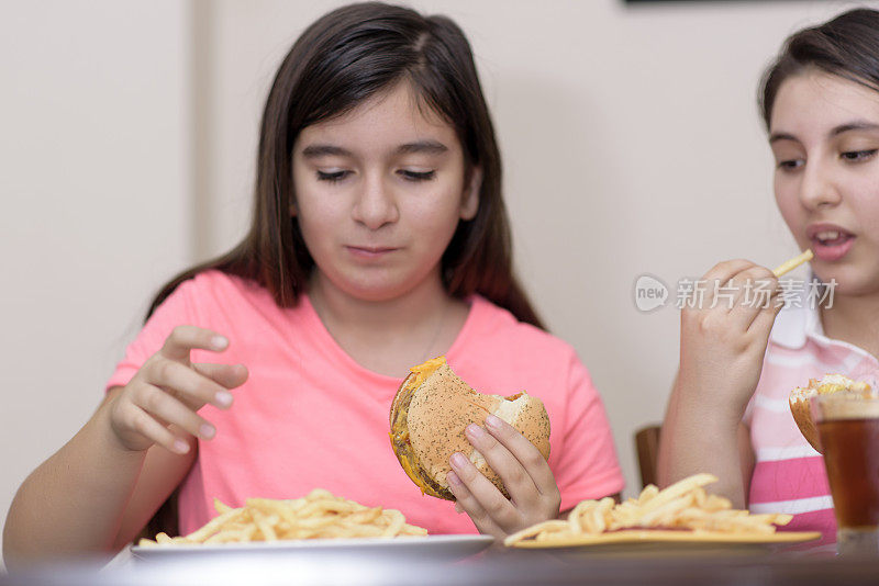 年轻女孩在室内吃汉堡