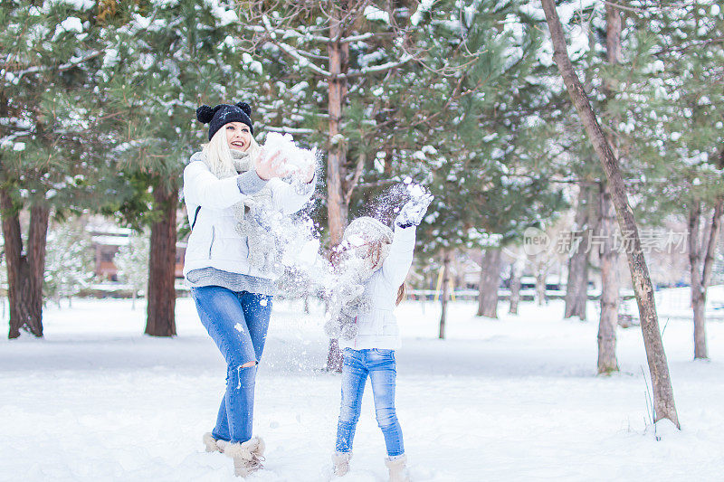 爱玩的妈妈和女儿在冬季公园。