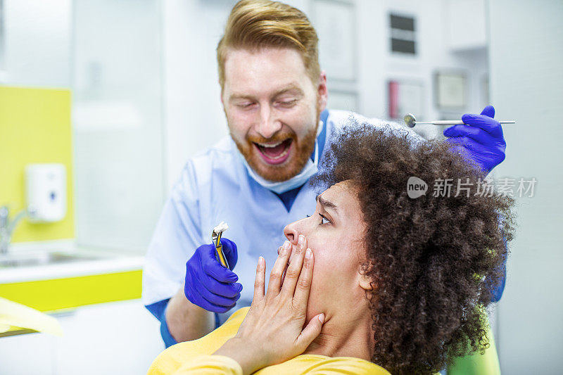 牙科技师用拔牙钳将一颗牙齿拔给一位休克中的妇女