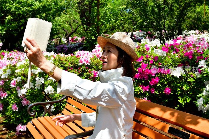 一名日本女子在公园里与盛开的杜鹃花自拍