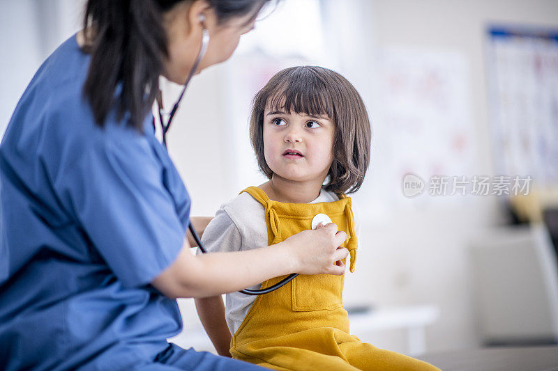 一个年轻的医生正在检查一个女孩的心脏