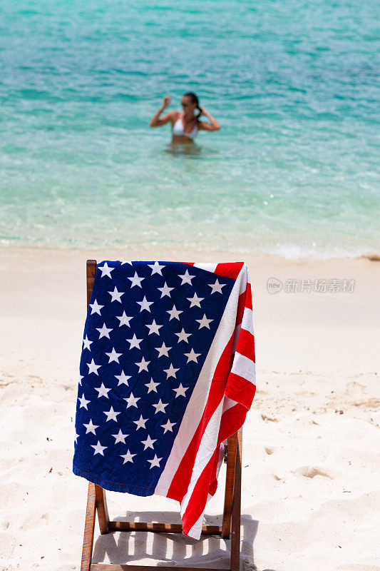 美国国旗毛巾在椅子上与女人在维尔京群岛热带海滩