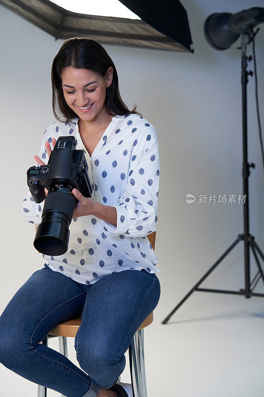 女性摄影师在摄影工作室拍摄与相机和照明设备