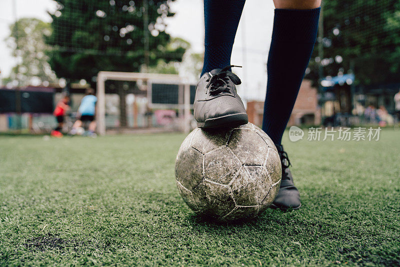 脚与足球的细节。有选择性的重点。孩子们在踢足球