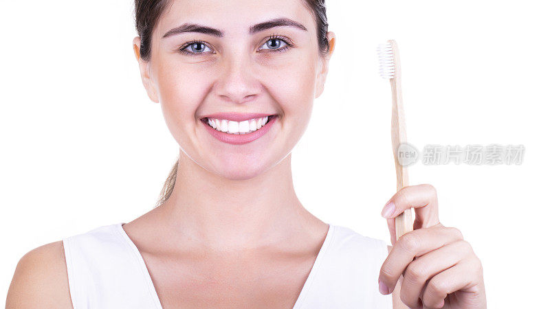 女人的微笑带着洁白健康的牙齿，手里拿着牙刷，孤立在白色