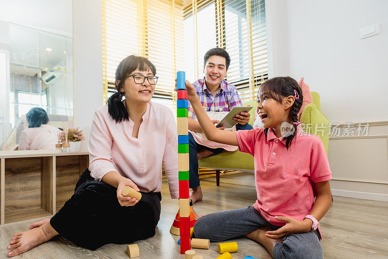 快乐的亚洲家庭玩玩具积木和花时间一起在家里的客厅
