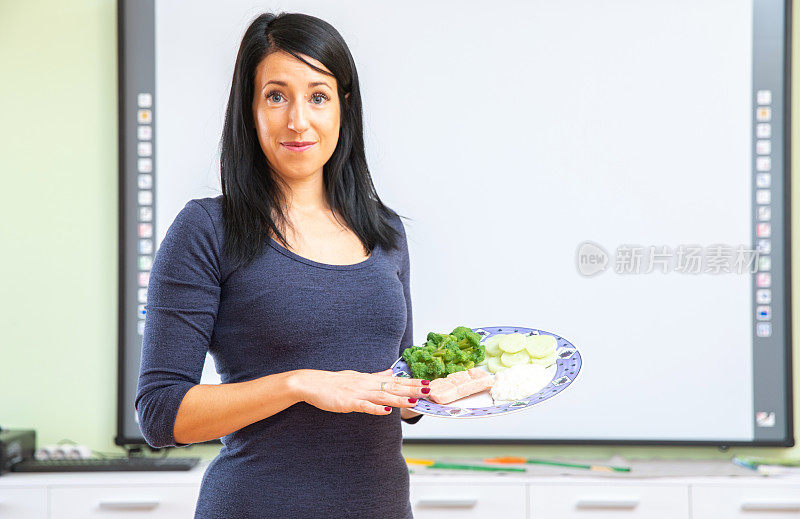 女性营养学家的肖像拿着一个盘子装满了平衡的主菜-库存照片