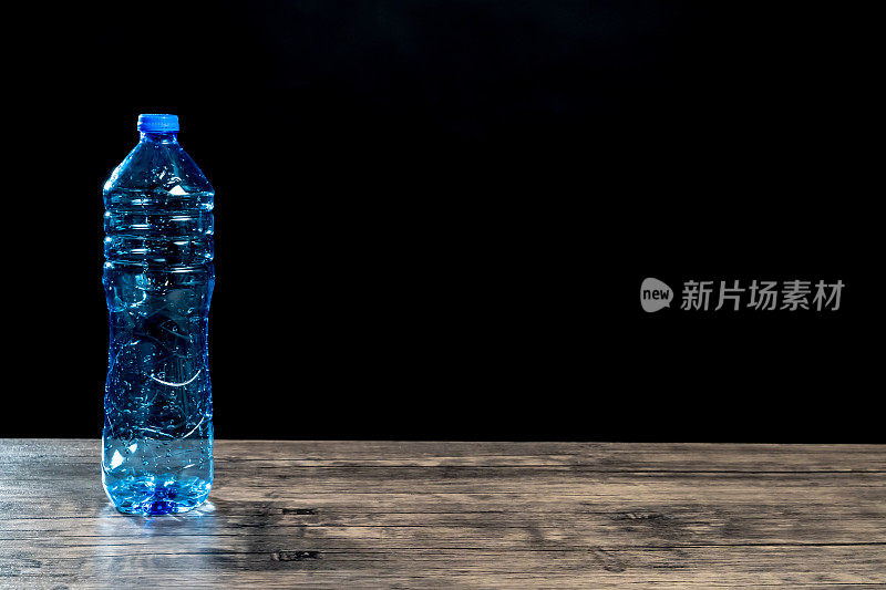 蓝色塑料瓶放在黑色背景的木桌上
