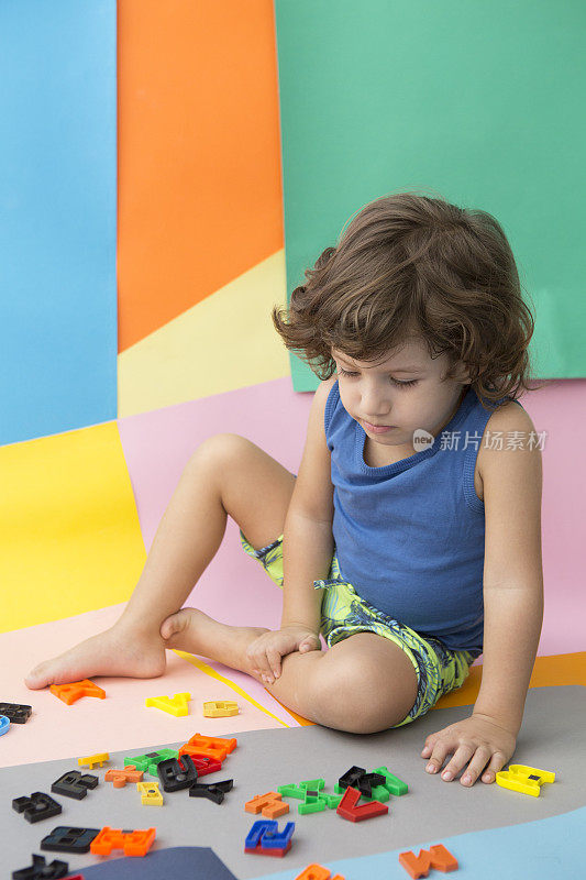 可爱的小男孩玩着五颜六色的字母