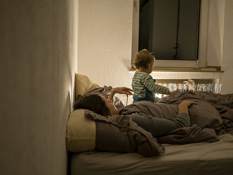 年轻的母亲和小男孩在卧室里快乐地玩耍