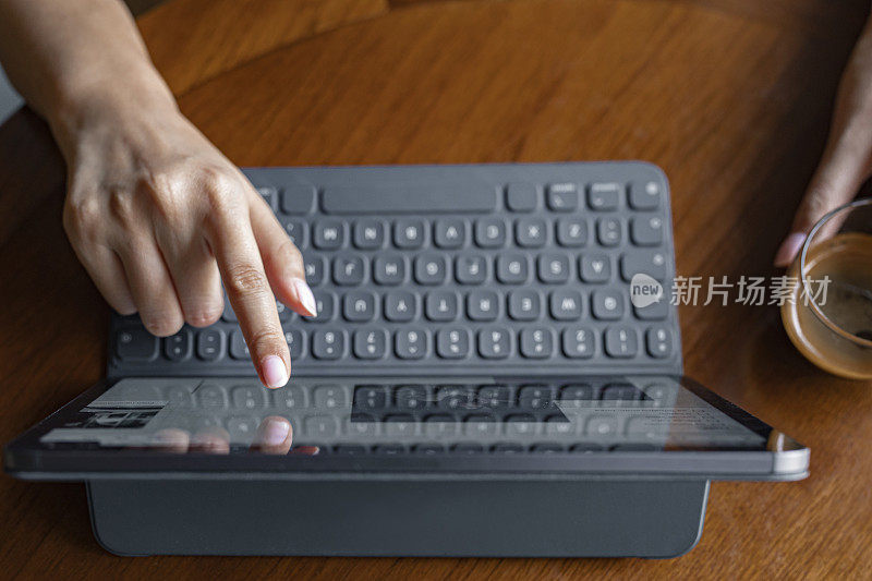 一个女人使用带键盘的平板电脑的手