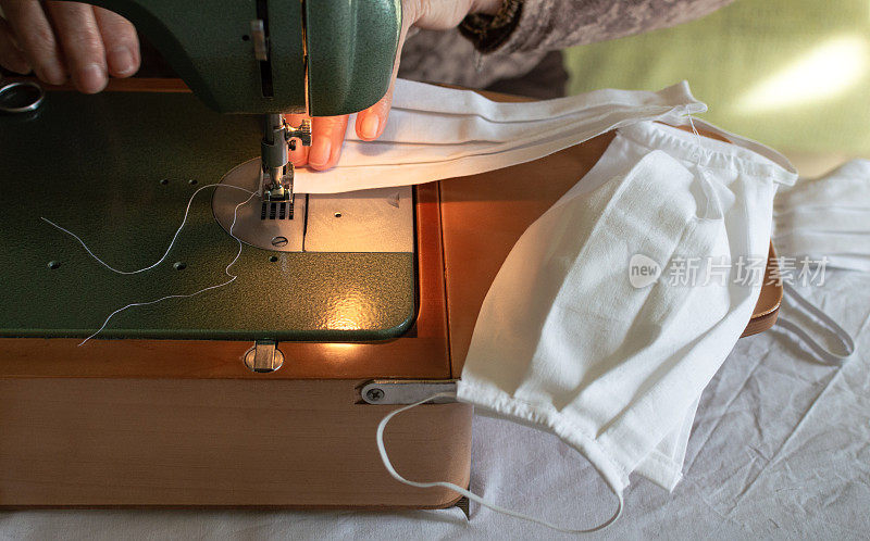 妇女用缝纫机在家里缝制医用口罩。防冠状病毒的手工防护口罩。