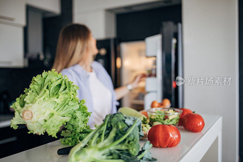 从冰箱里拿食材做素食沙拉的女人